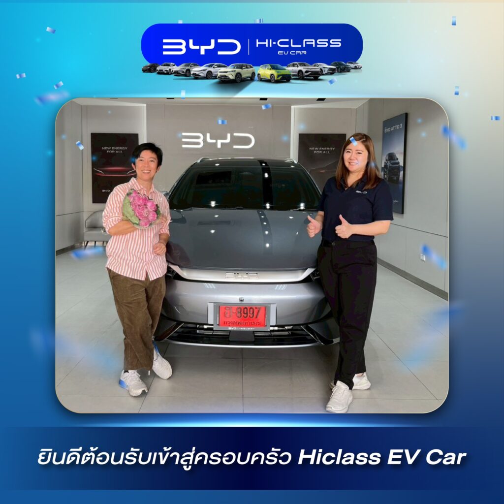 ภาพส่งมอบรถยนต์ไฟฟ้า BYD สีขาวป้ายแดง ลูกค้าผู้ชายถ่ายภาพคู่กับที่ปรึกษาการขายถือช่อดอกไม้ ที่โชว์รูม BYD Hi-Class สาขาบองมาเช่